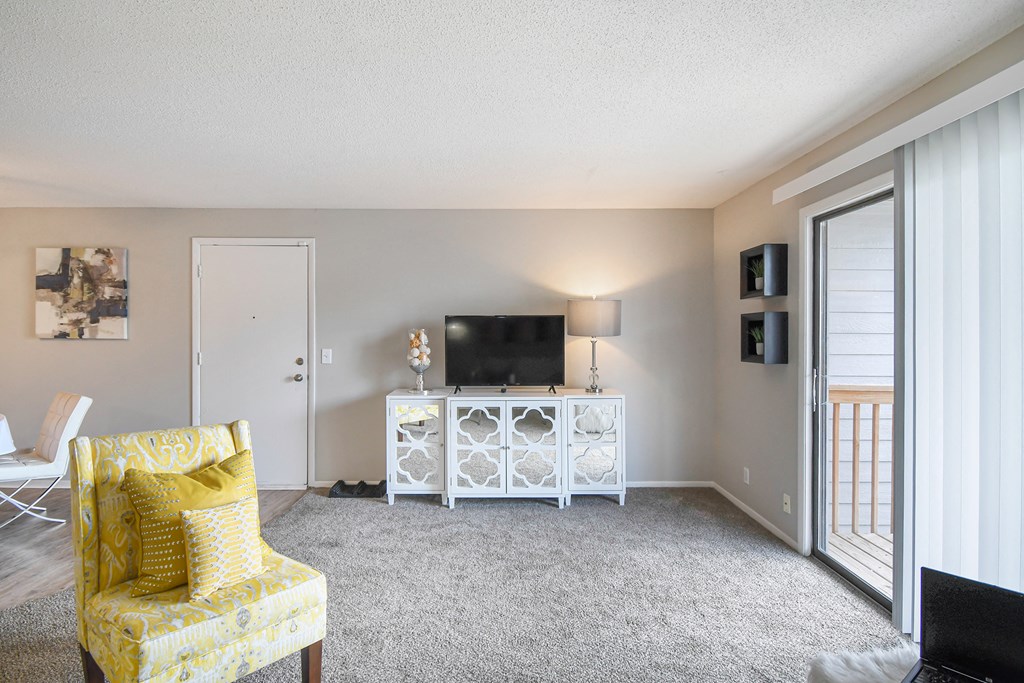 a living room with a yellow chair and a television