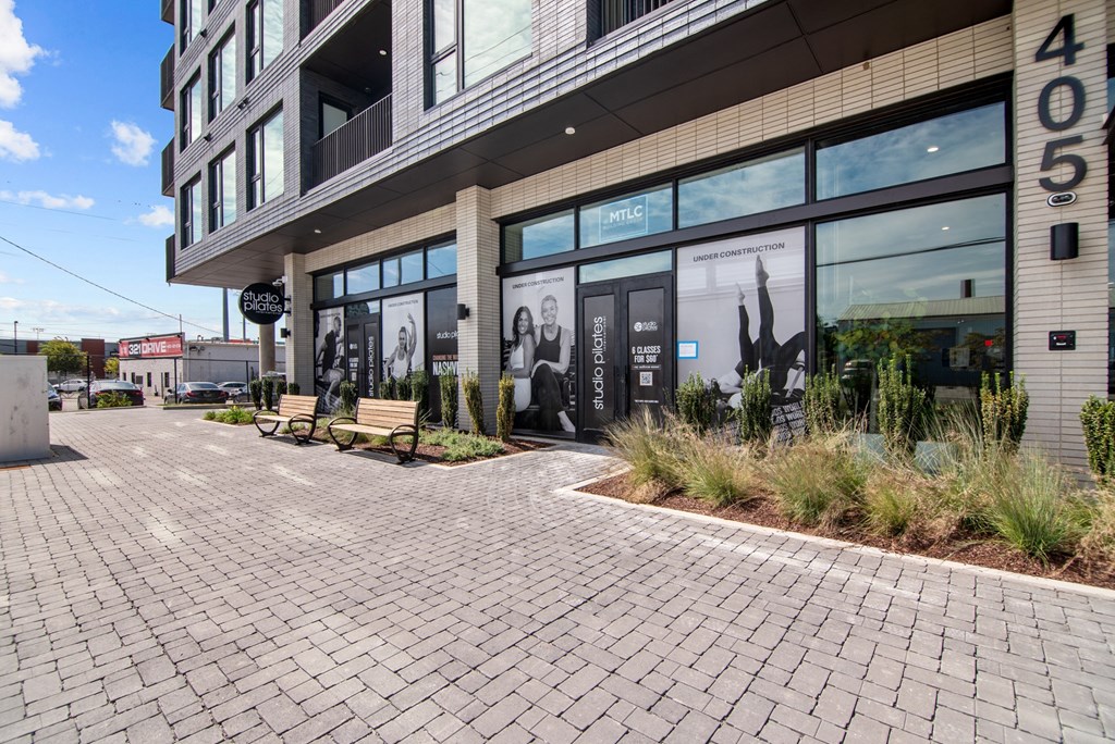 a brick sidewalk in front of a building with large windows