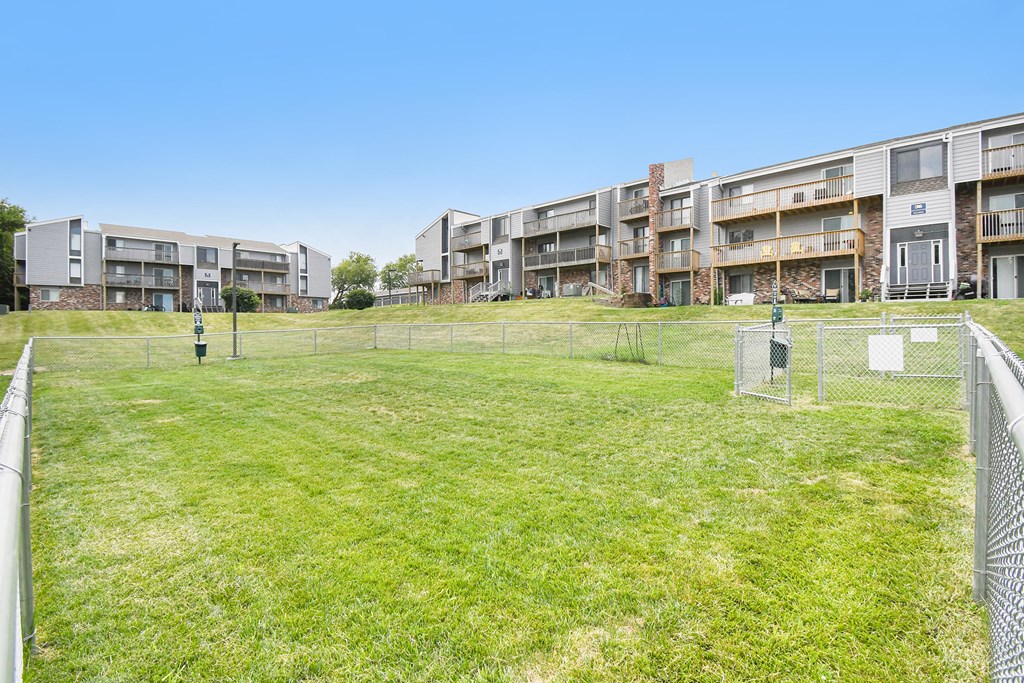 a fenced in soccer field in front of an apartment building