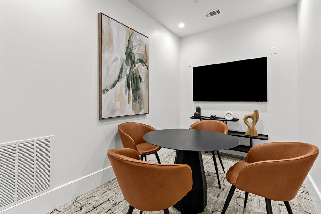 A modern dining room with a large painting on the wall and a flat screen TV mounted above the table.