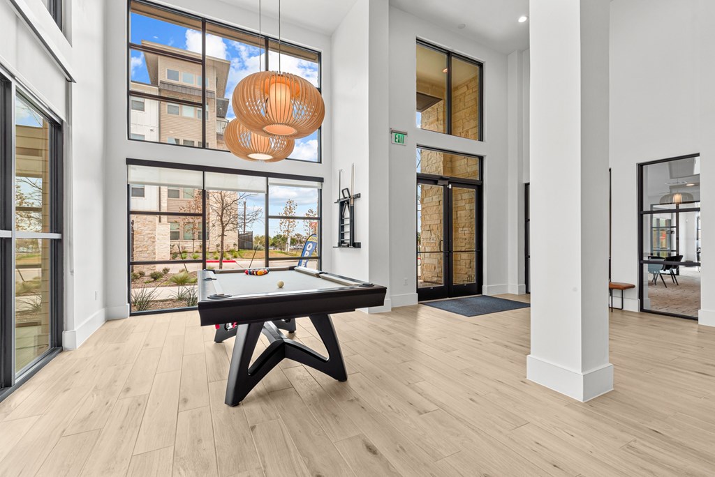 A room with a pool table and a view of a building outside the window.