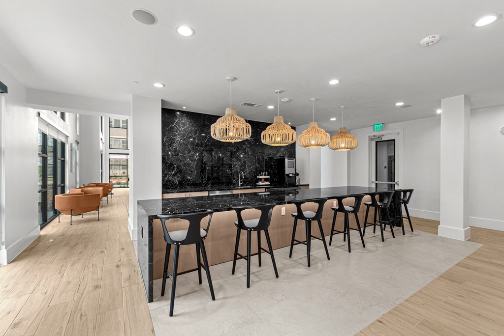 A modern kitchen with a black marble backsplash and a long bar with stools.