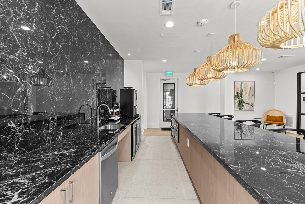 A modern kitchen with marble countertops and wooden cabinets.