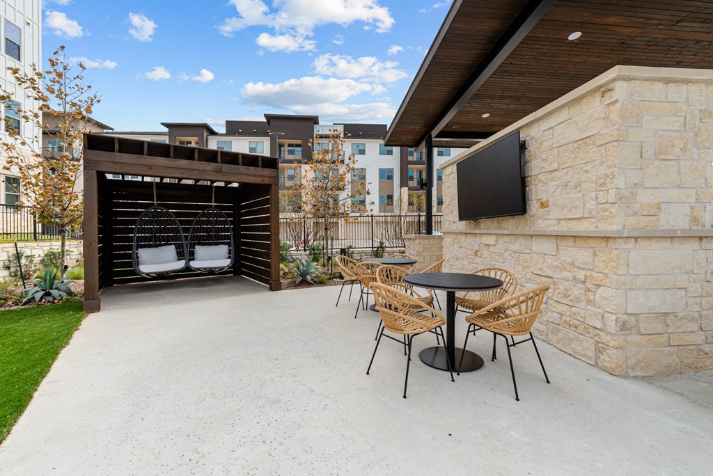 A patio with a table and chairs and a TV on the wall.