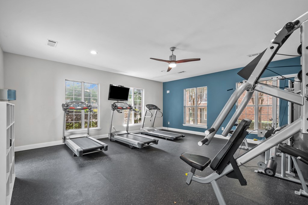 A spacious home gym with treadmills, a stationary bike, and a weight bench.