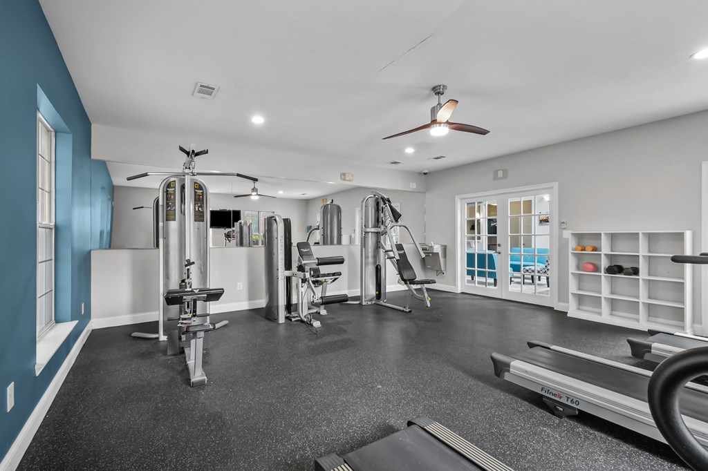 A spacious home gym with a variety of equipment including a treadmill, weights, and a bench press.