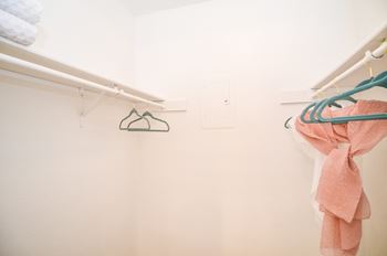 a white closet with towels and a hanger on the wall