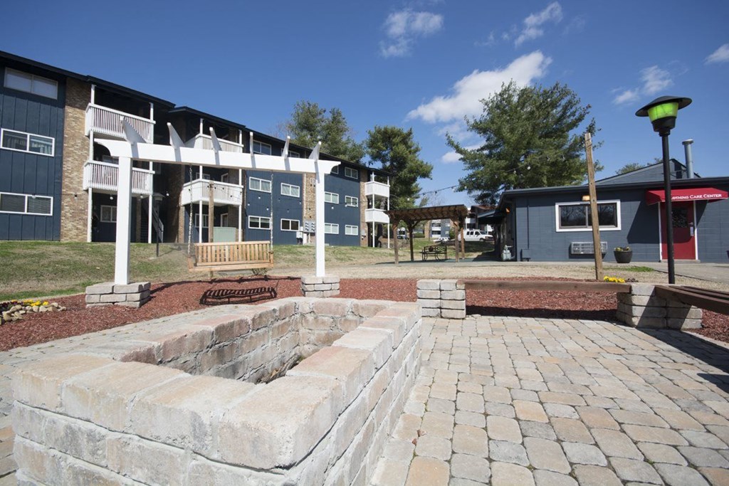 a fire pit sits in the middle of a brick patio in front of a building