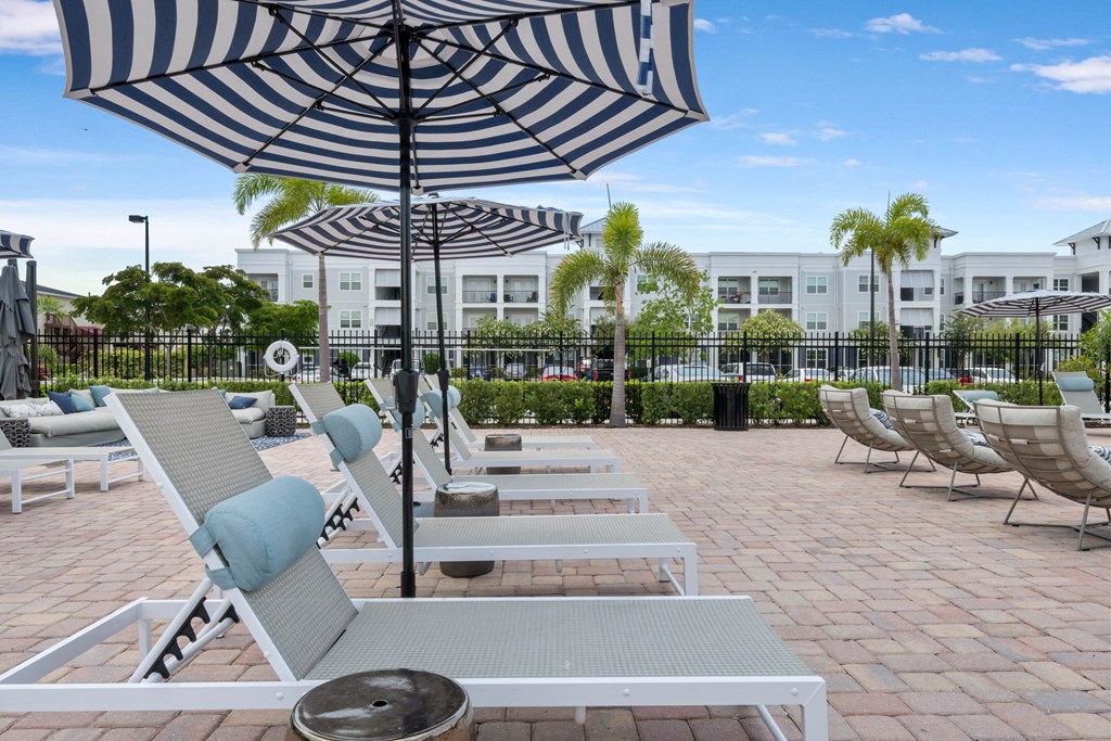 a pool with lounge chairs and umbrellas in front of a building