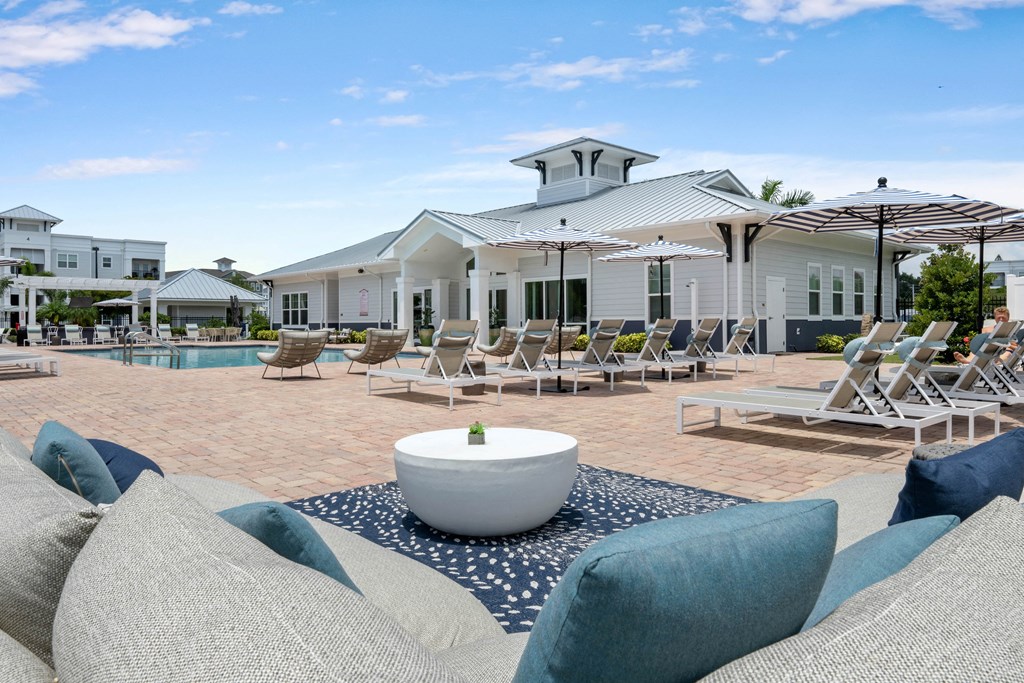 a pool with lounge chairs and umbrellas at the enclave at woodbridge apartments in sugar