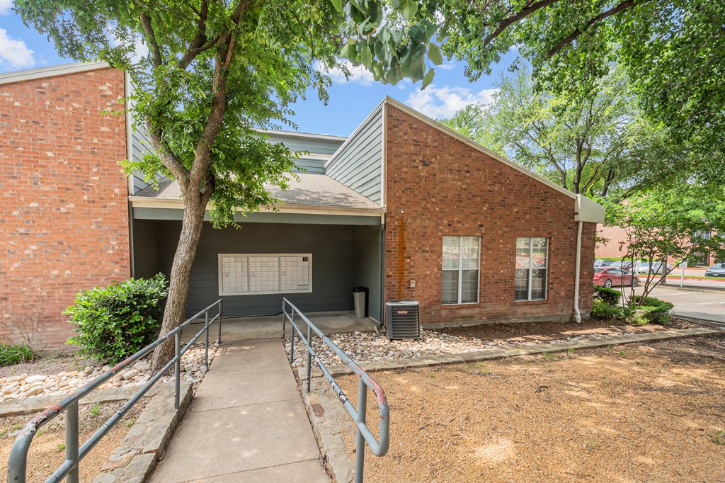 A brick building with a metal roof and a tree in front.