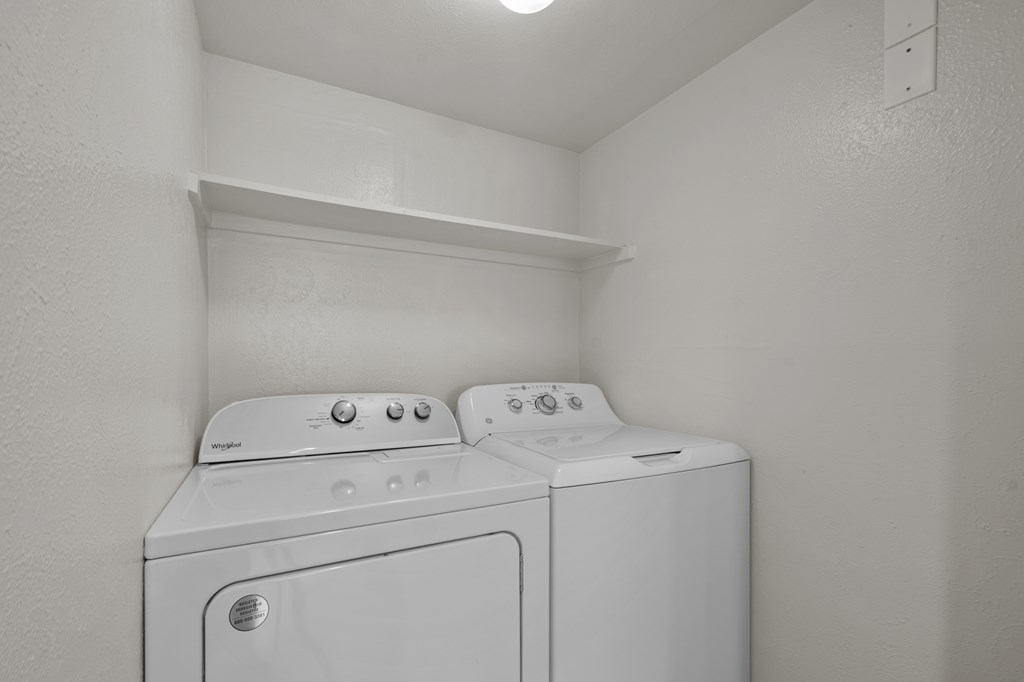 Two white washing machines in a small laundry room.