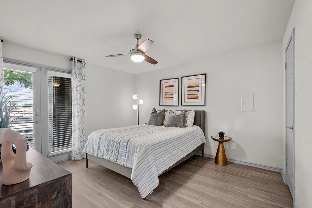 A bedroom with a bed, a ceiling fan, and a window with blinds.