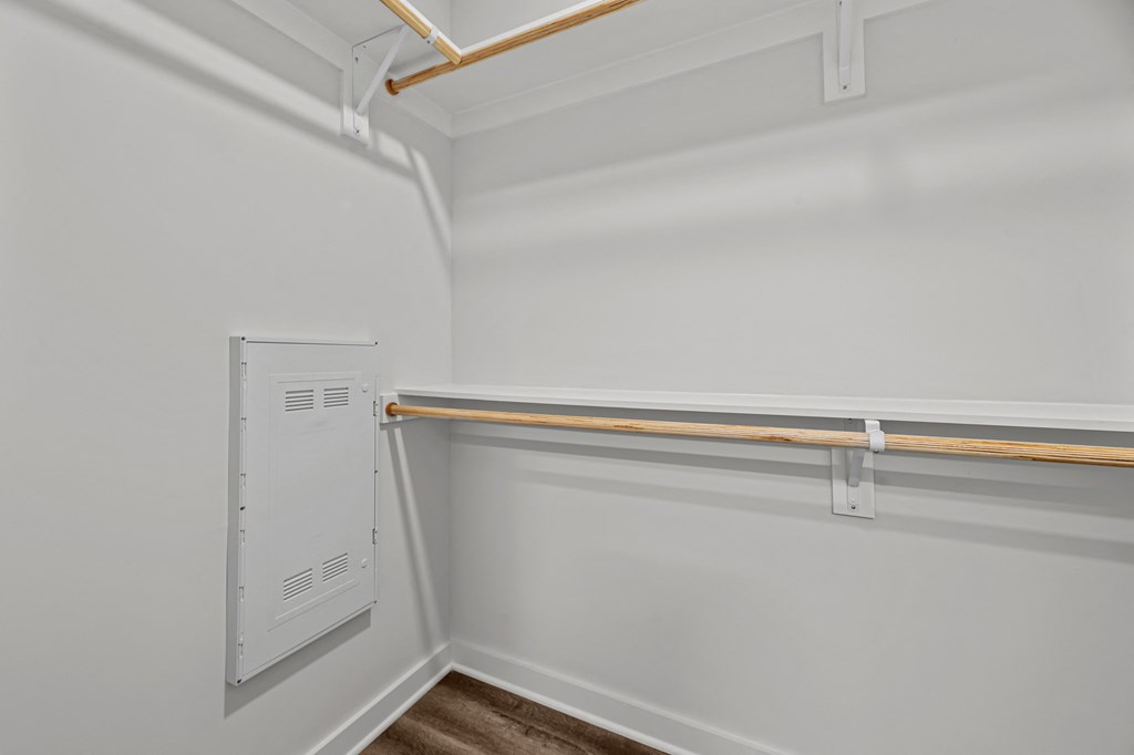 A white wall with a white electrical box and a white shelf.