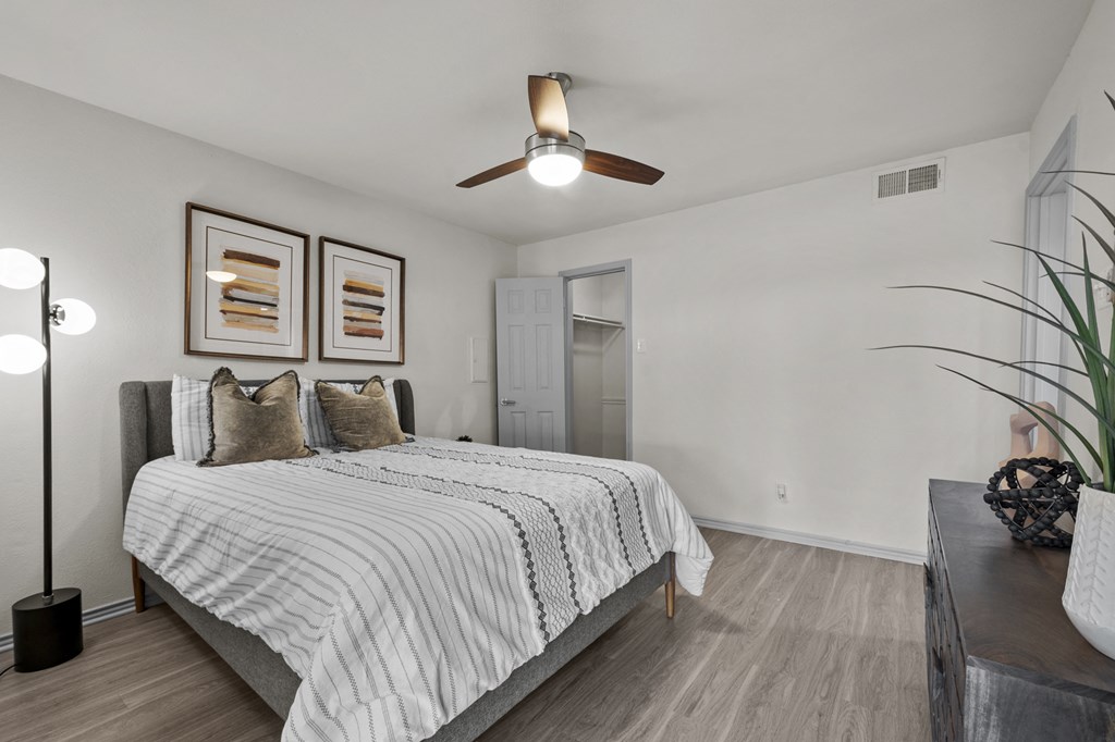 A bedroom with a bed, a ceiling fan, and two picture frames on the wall.