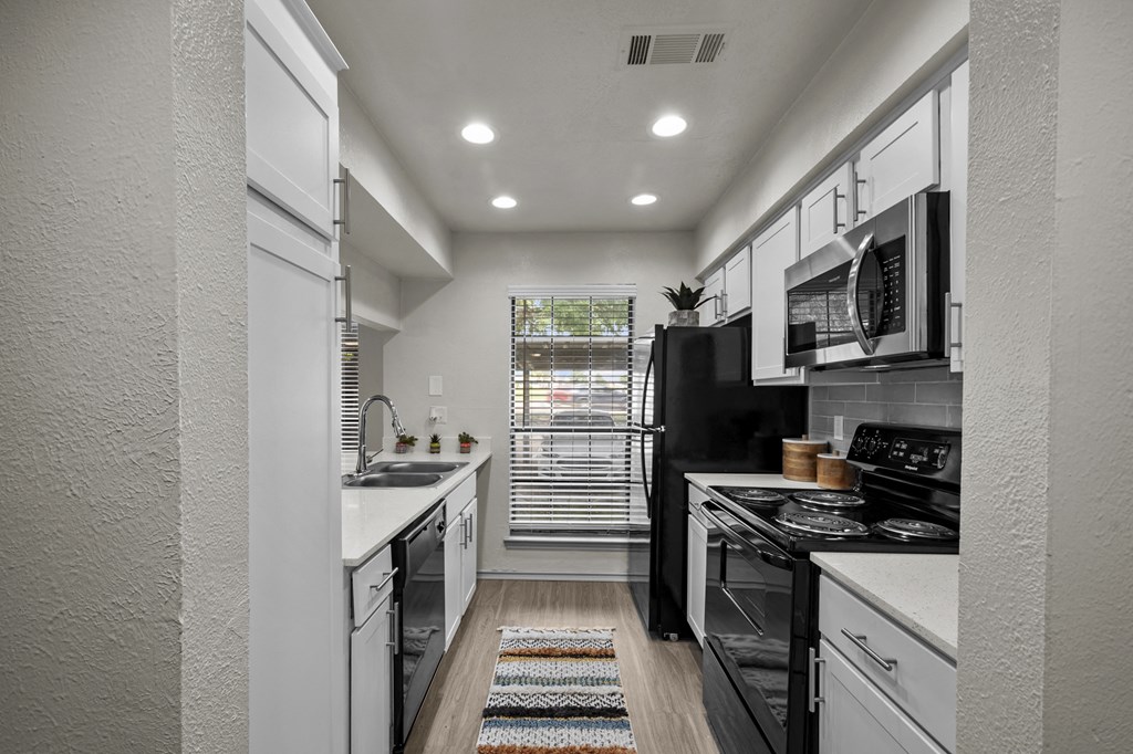 A modern kitchen with black appliances and white cabinets.