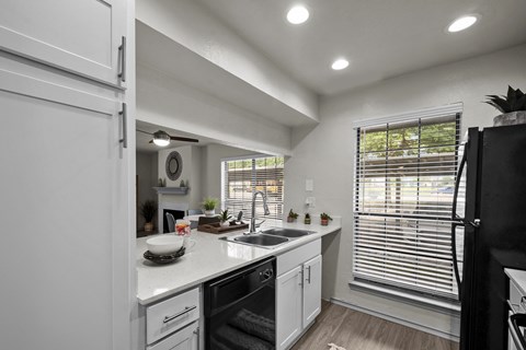A modern kitchen with white cabinets and a black refrigerator.