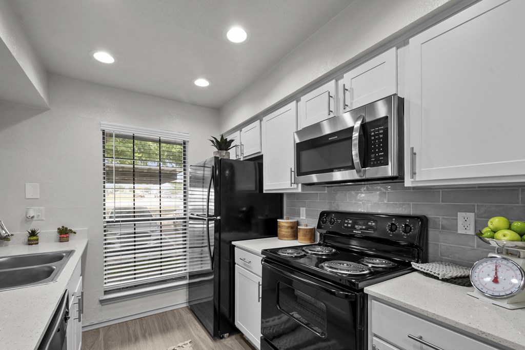 A modern kitchen with a black refrigerator, stove, and microwave.
