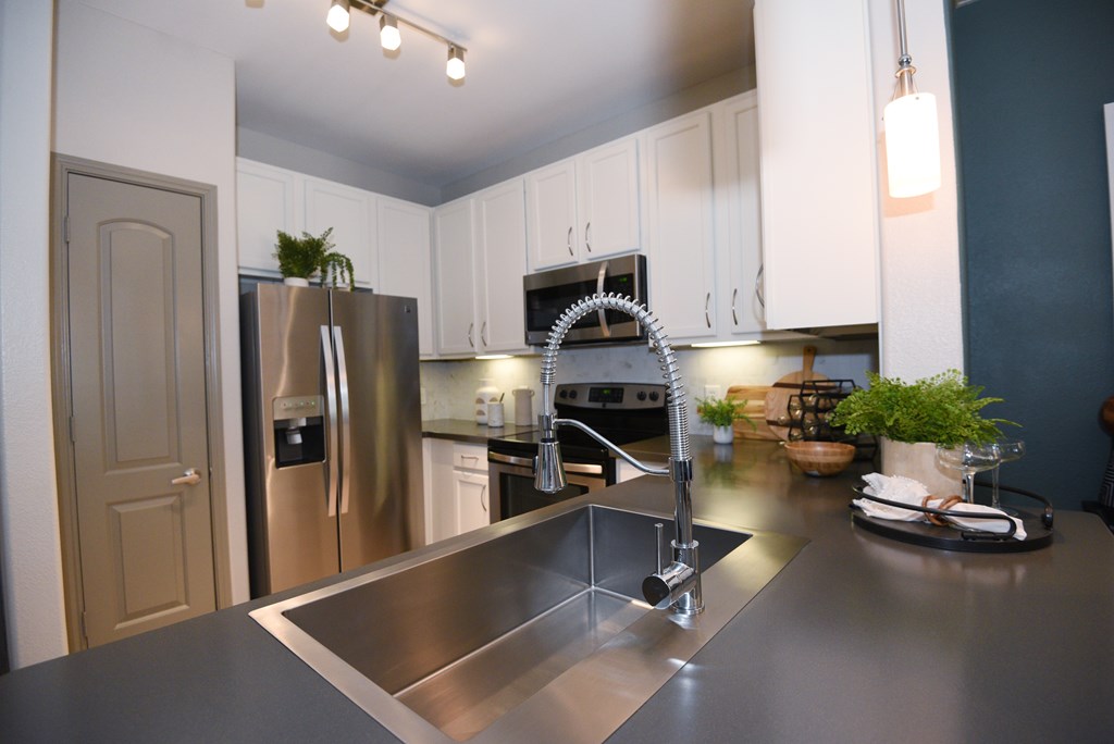 A modern kitchen with a stainless steel sink and refrigerator.