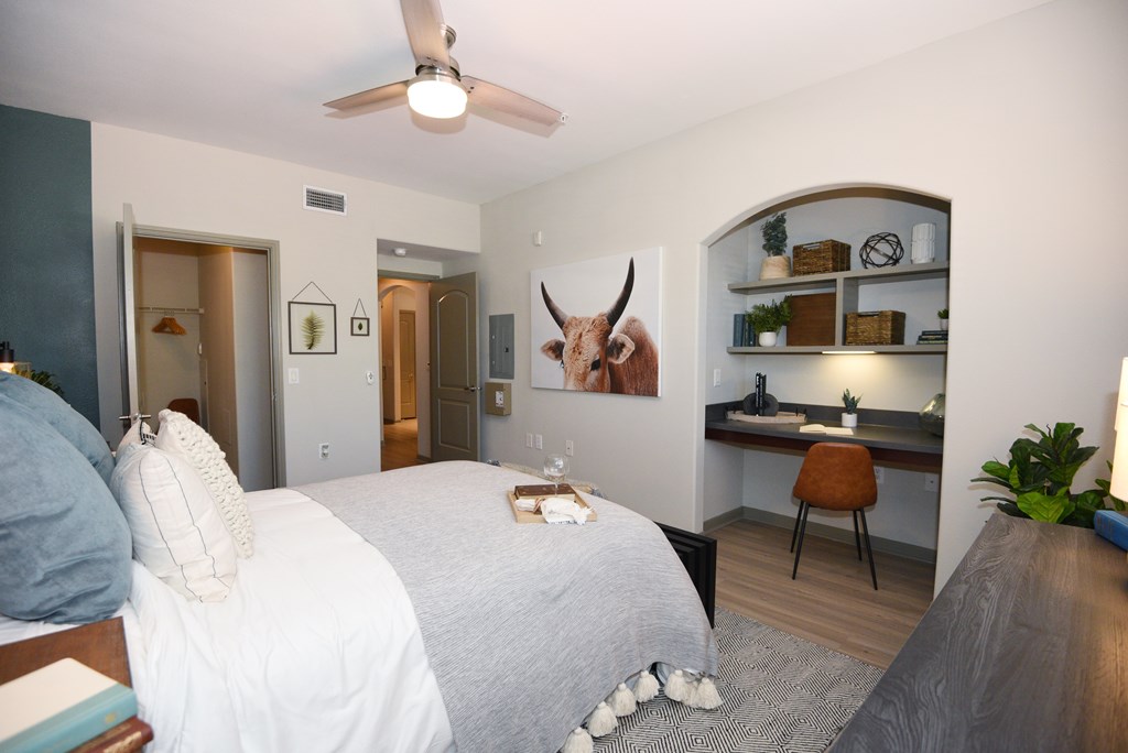 A bedroom with a bed, desk, and a painting of a bull on the wall.
