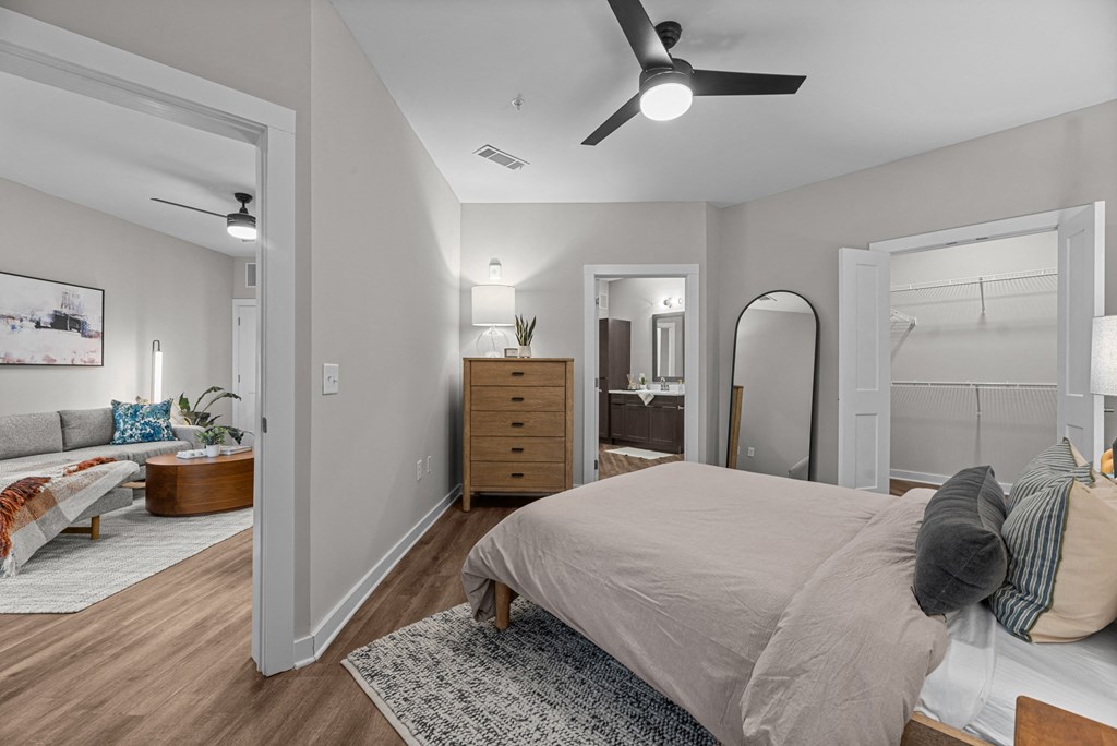 A bedroom with a bed, dresser, mirror, and a ceiling fan.