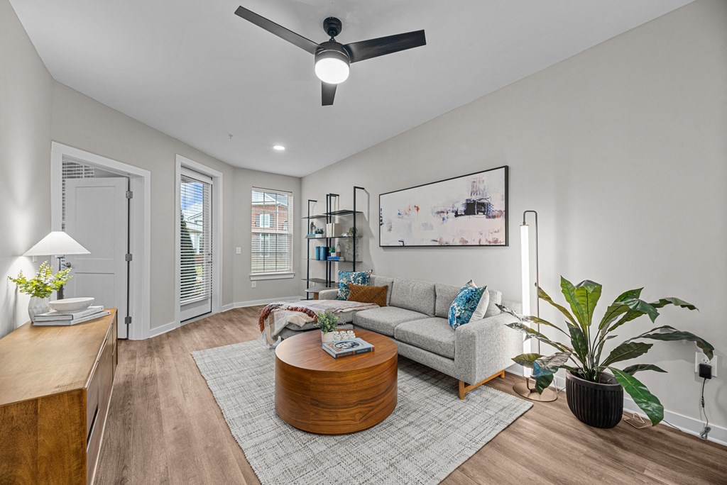A living room with a grey couch, a coffee table, a potted plant, and a painting on the wall.