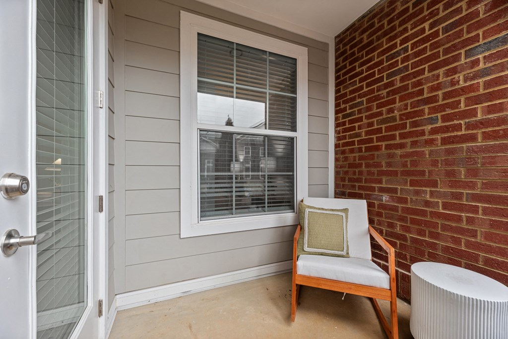 A chair with a pillow is placed in front of a window.