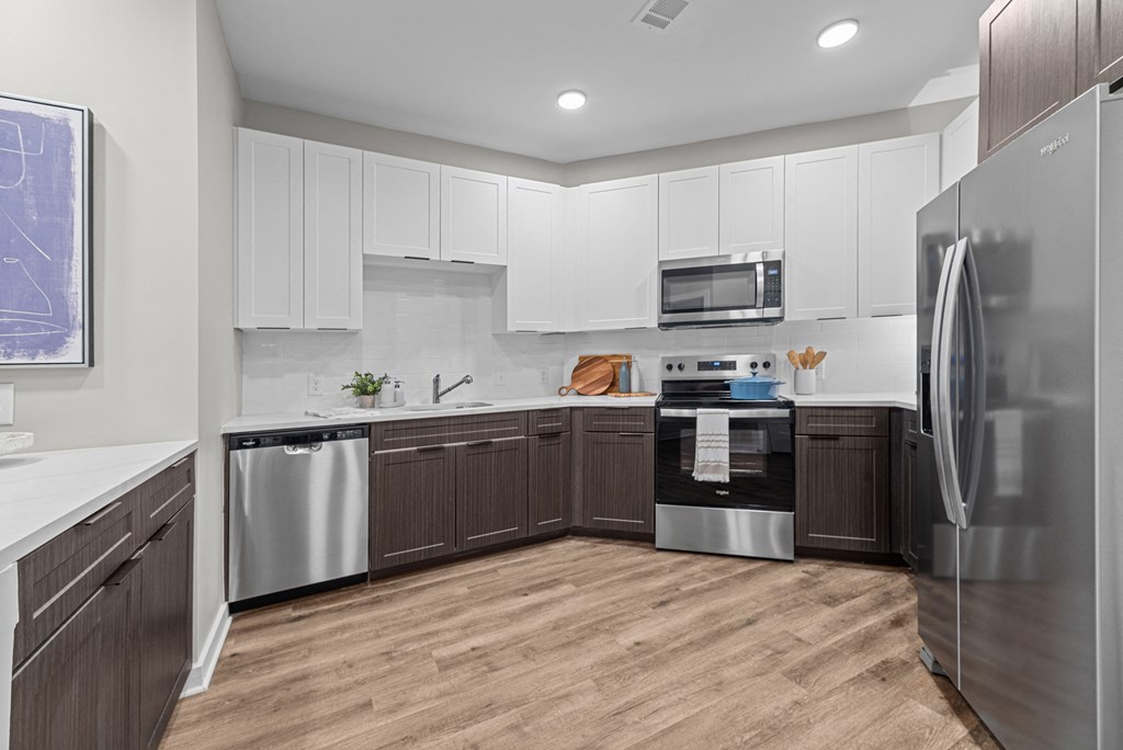 A modern kitchen with wooden floors and stainless steel appliances.