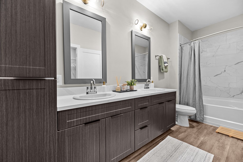 A modern bathroom with a double sink vanity and a shower area.
