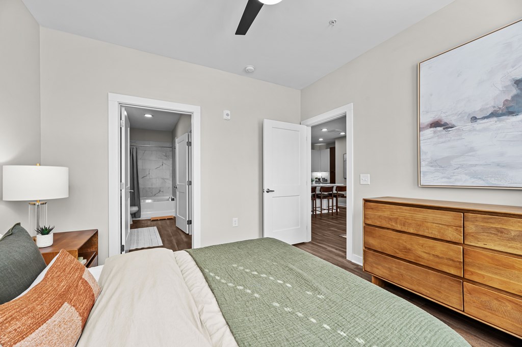 A bedroom with a bed, dresser, and painting on the wall.