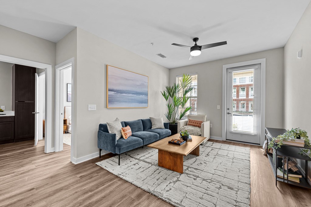 A living room with a blue couch and a painting on the wall.