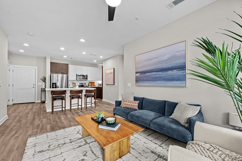 A living room with a blue couch and a painting on the wall.