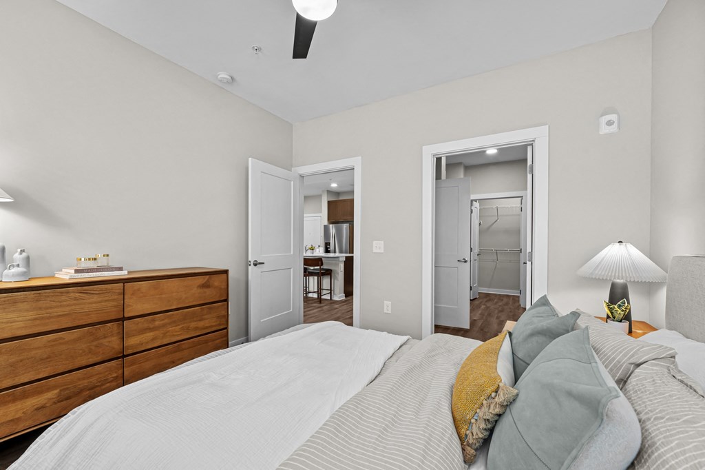 A bedroom with a bed, dresser, and two doors.