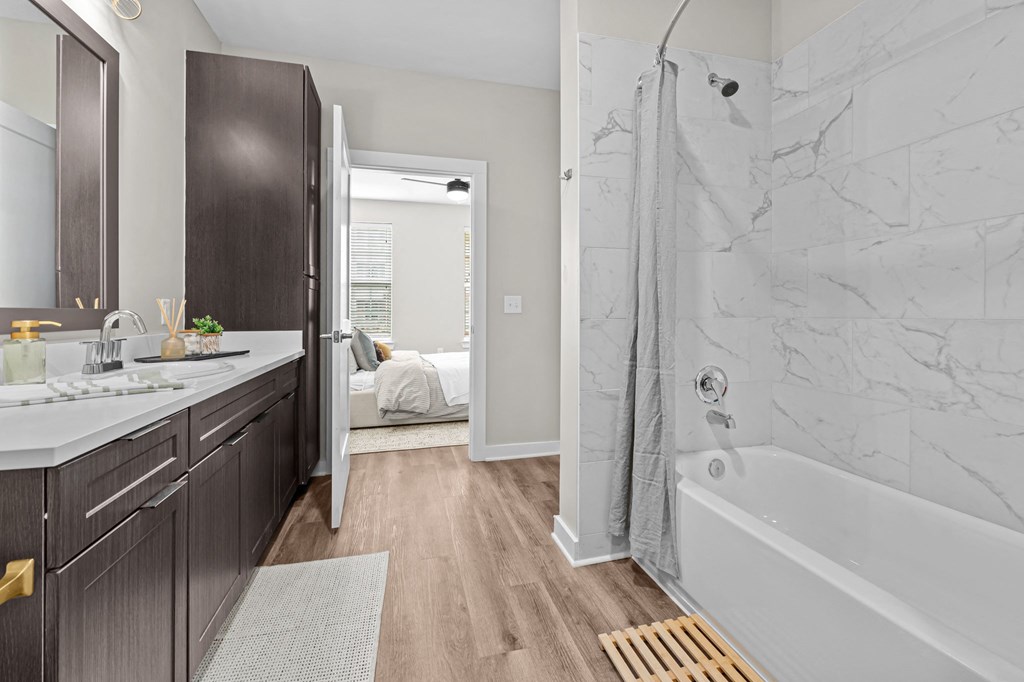 A bathroom with a marble wall and a wooden floor.