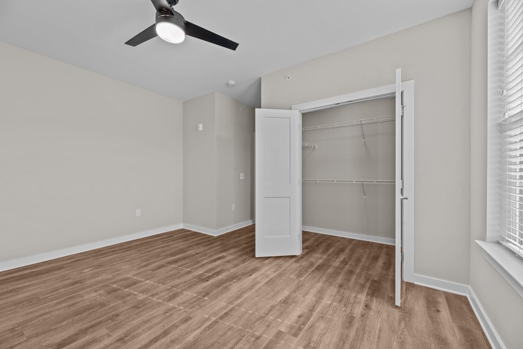 A room with a ceiling fan and a white closet.