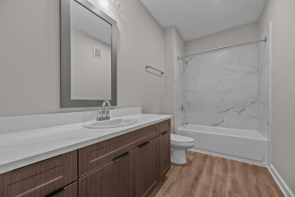 A bathroom with a marble shower and wooden cabinets.