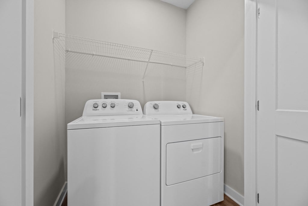 Two white washing machines in a small laundry room.