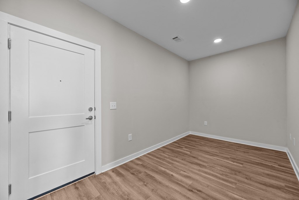 A room with a white door and wooden floor.