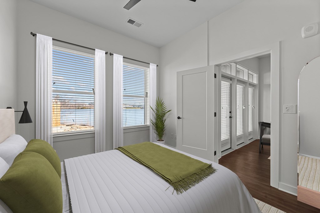 A bedroom with a bed, a chair, and a plant.