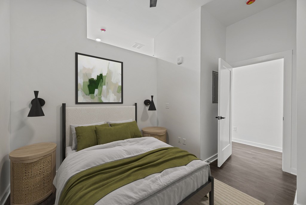 A bedroom with a bed, nightstand, and a painting on the wall.