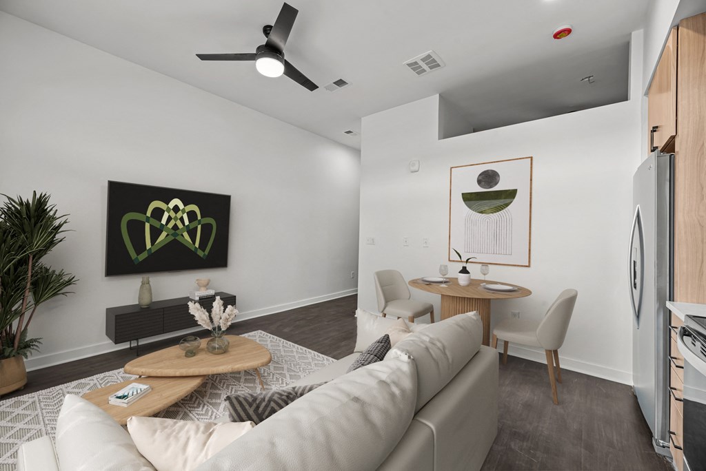 A living room with a white couch and a coffee table with a vase of flowers on it.