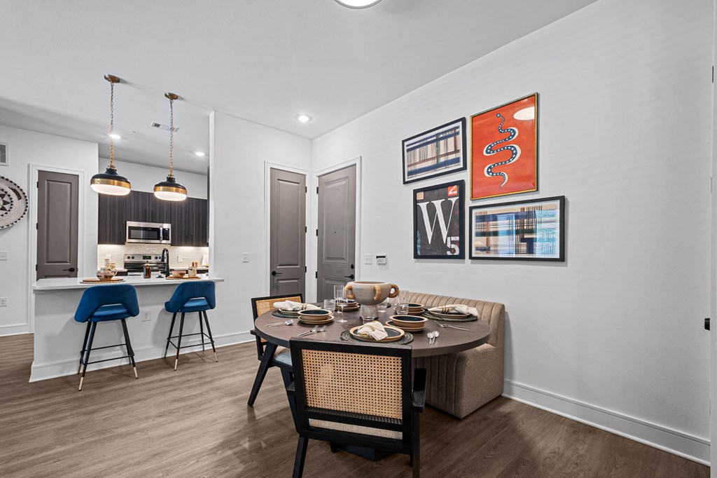 a dining area with a table and chairs and a kitchen in the background