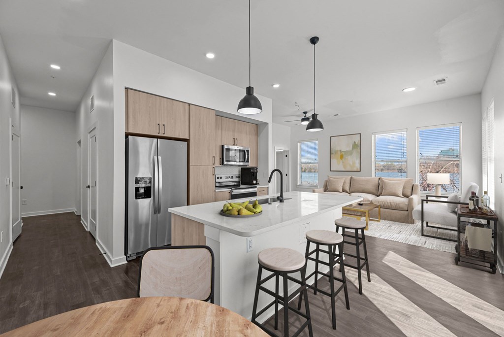 A modern kitchen with a refrigerator, sink, and bar stools.