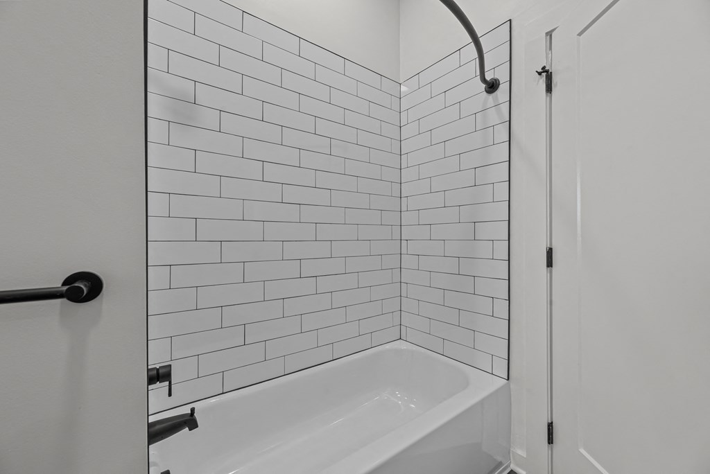 A white bathroom with a white tub and white tiles.