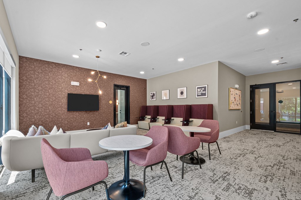 a lounge area with tables and chairs and a television