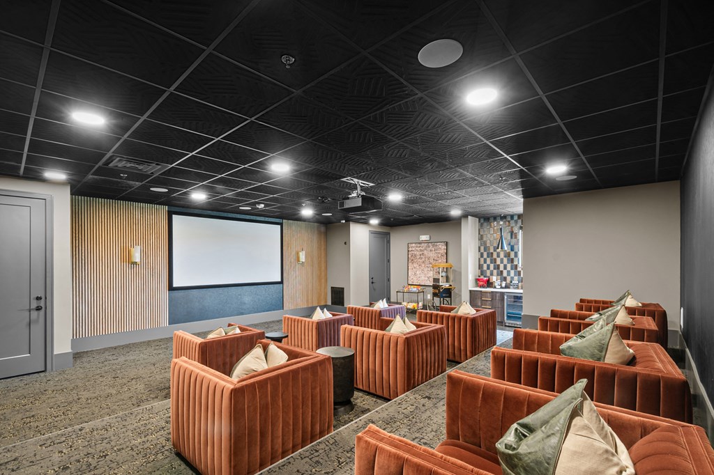 a large room with brown couches and a projector screen