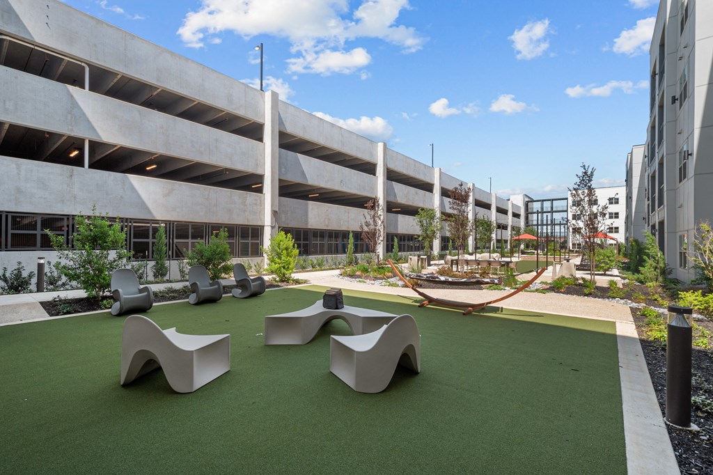 a courtyard with benches and grass in front of a building
