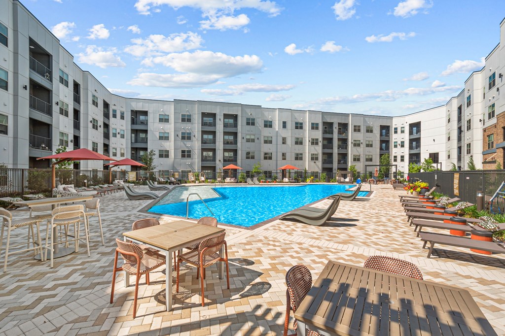 an outdoor pool with tables and chairs at an apartment building