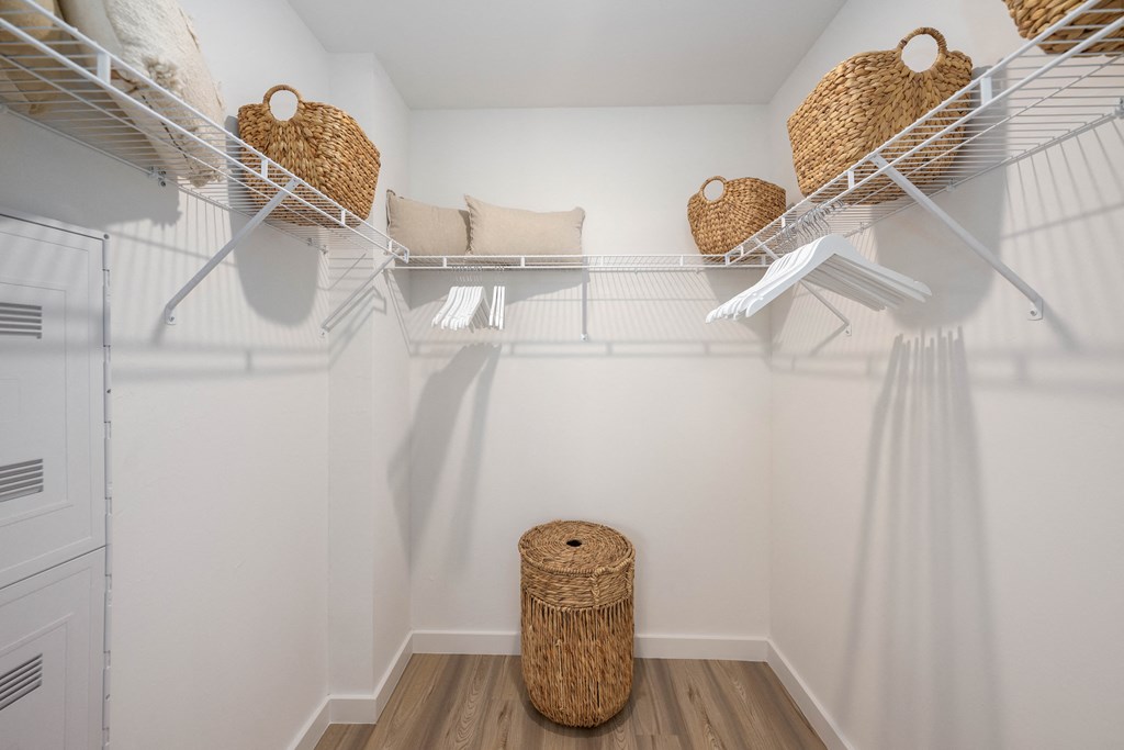 a walk in closet with white walls and wicker baskets