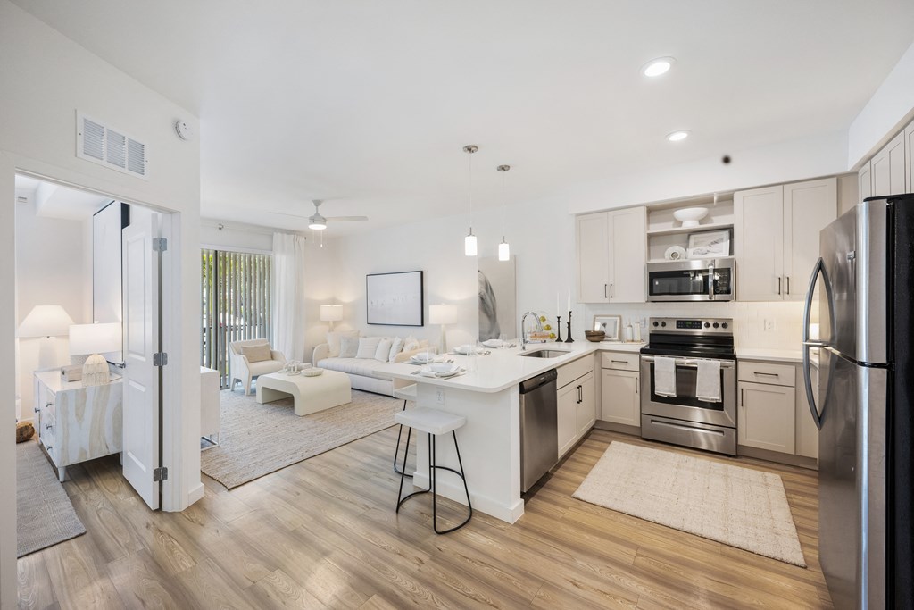 a kitchen and living room with white walls and hardwood floors
